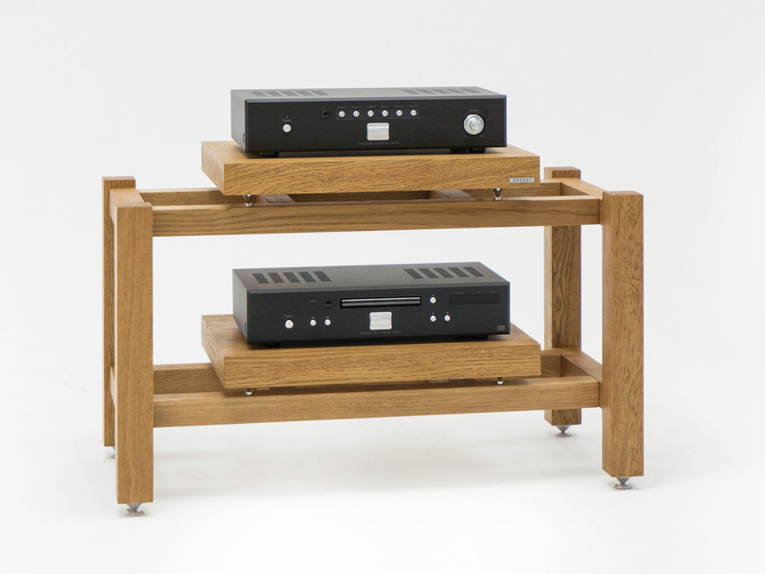 Kunsst rack for audio equipment with a hi-fi amplifier on the top shelf and a CD player on the lower shelf, standing on a white background.