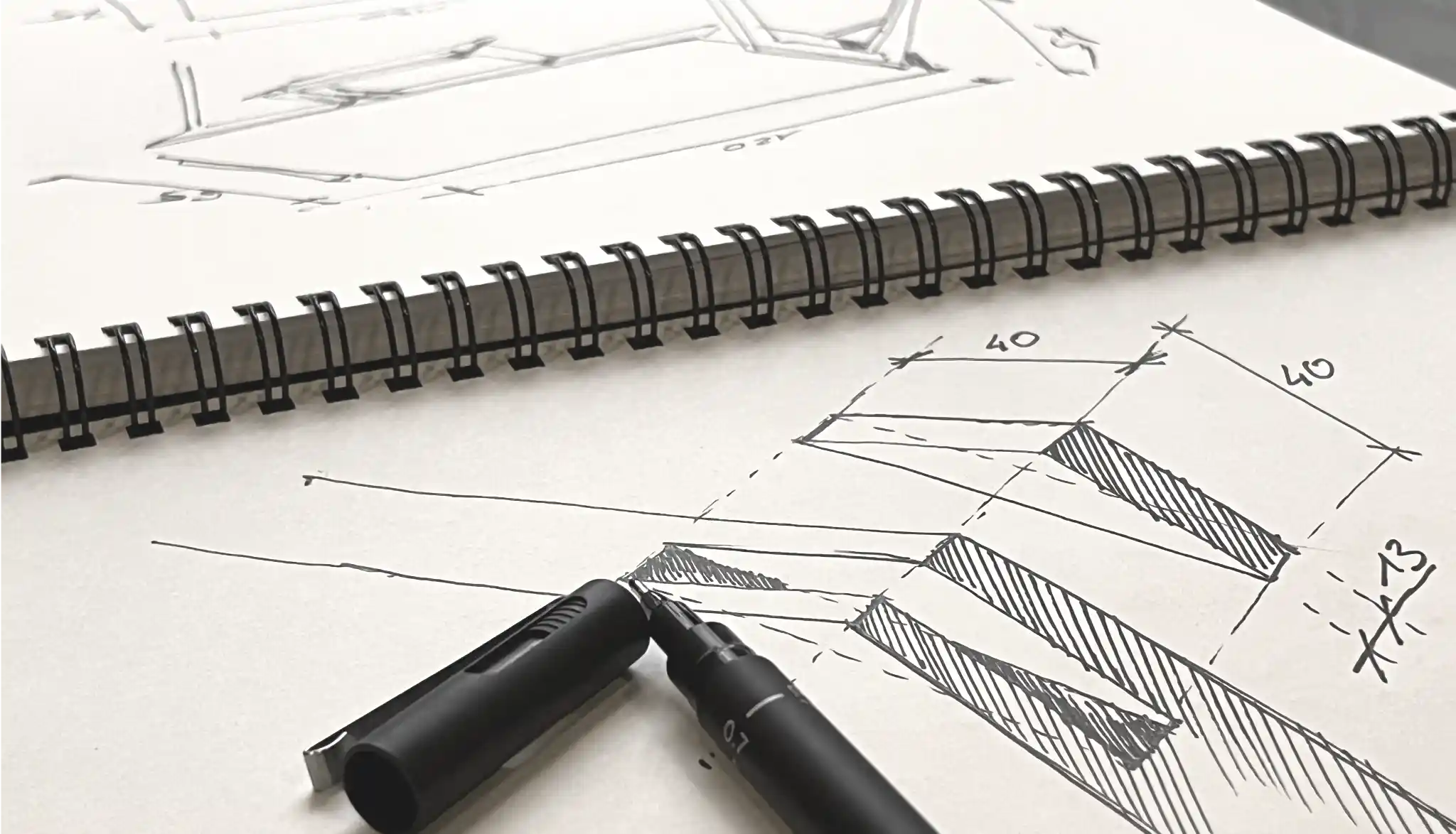 Design sketches of wooden desk on a notebook with a pen on a white paper