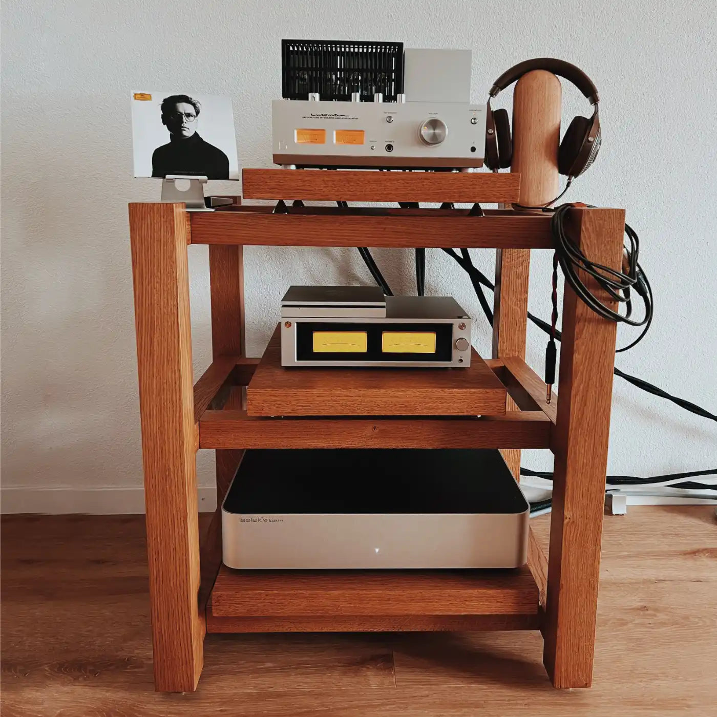 Kunsst wooden audio rack with a Luxman SQ-N150 tube amplifier on top and an IsoTek Elektra power conditioner and HiFi Rose streamer on the lower shelves, standing in a living room on a wooden floor.
