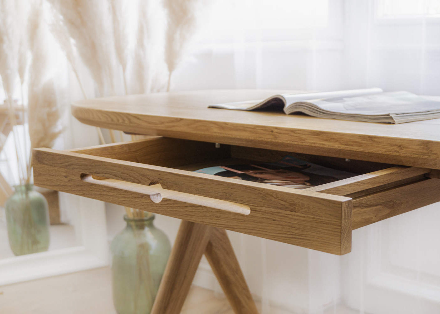 Kunsst solid wooden desk with a drawer open, showing a magazine inside, standing in a vanity room.