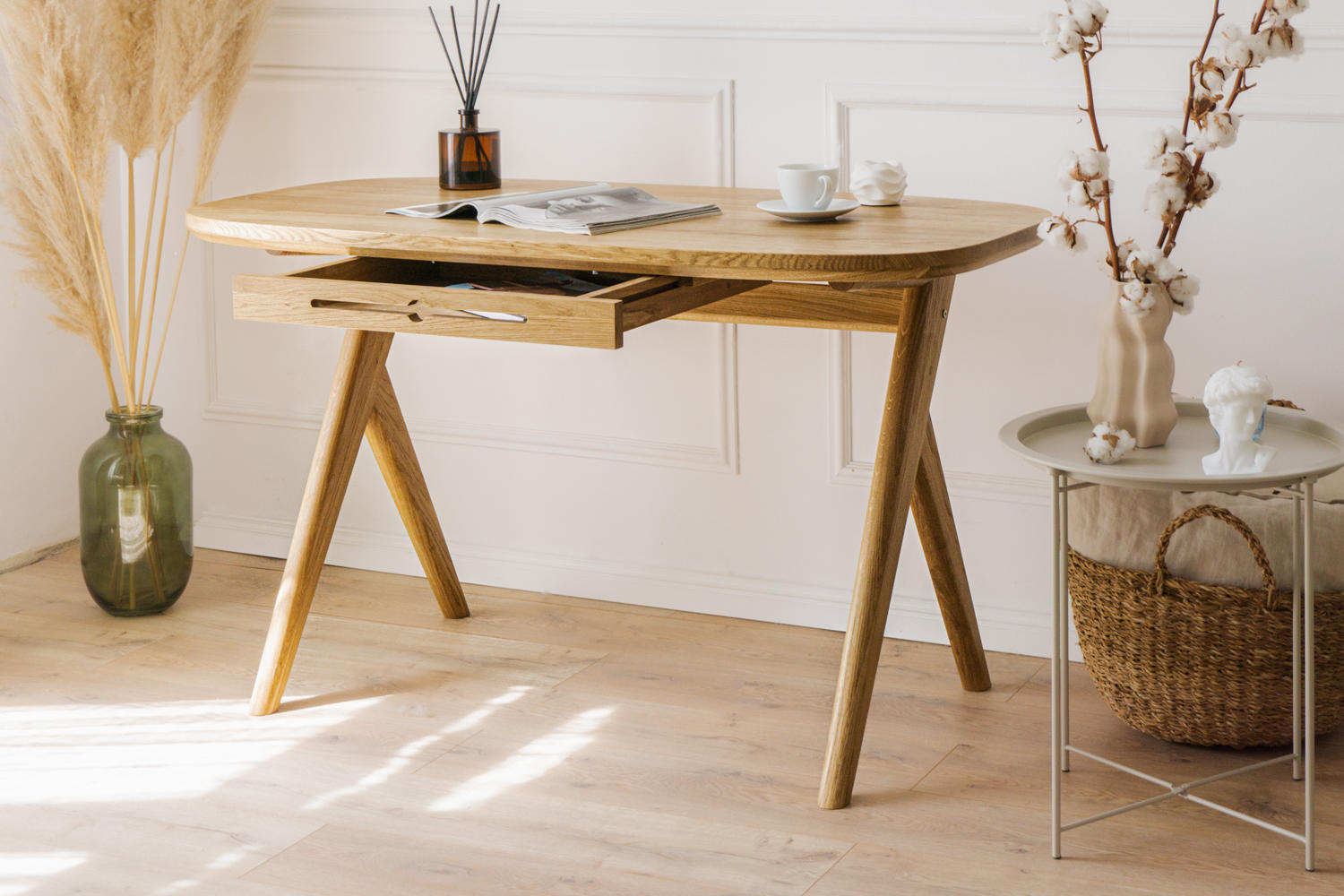 Kunsst vintage desk for a vanity with smooth rounded edges is showcased in a bright, luxury living room with elegant mouldings and decorative items. A magazine and a cup of coffee are placed on the solid wood desk top.