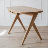 Kunsst mid century modern desk for small spaces placed in a elegant living room with warm wooden flooring. The white wall behind features  classic moulding.