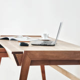 Solid wood desk with drawer standing on white background with MacBook and magazine on oak desktop