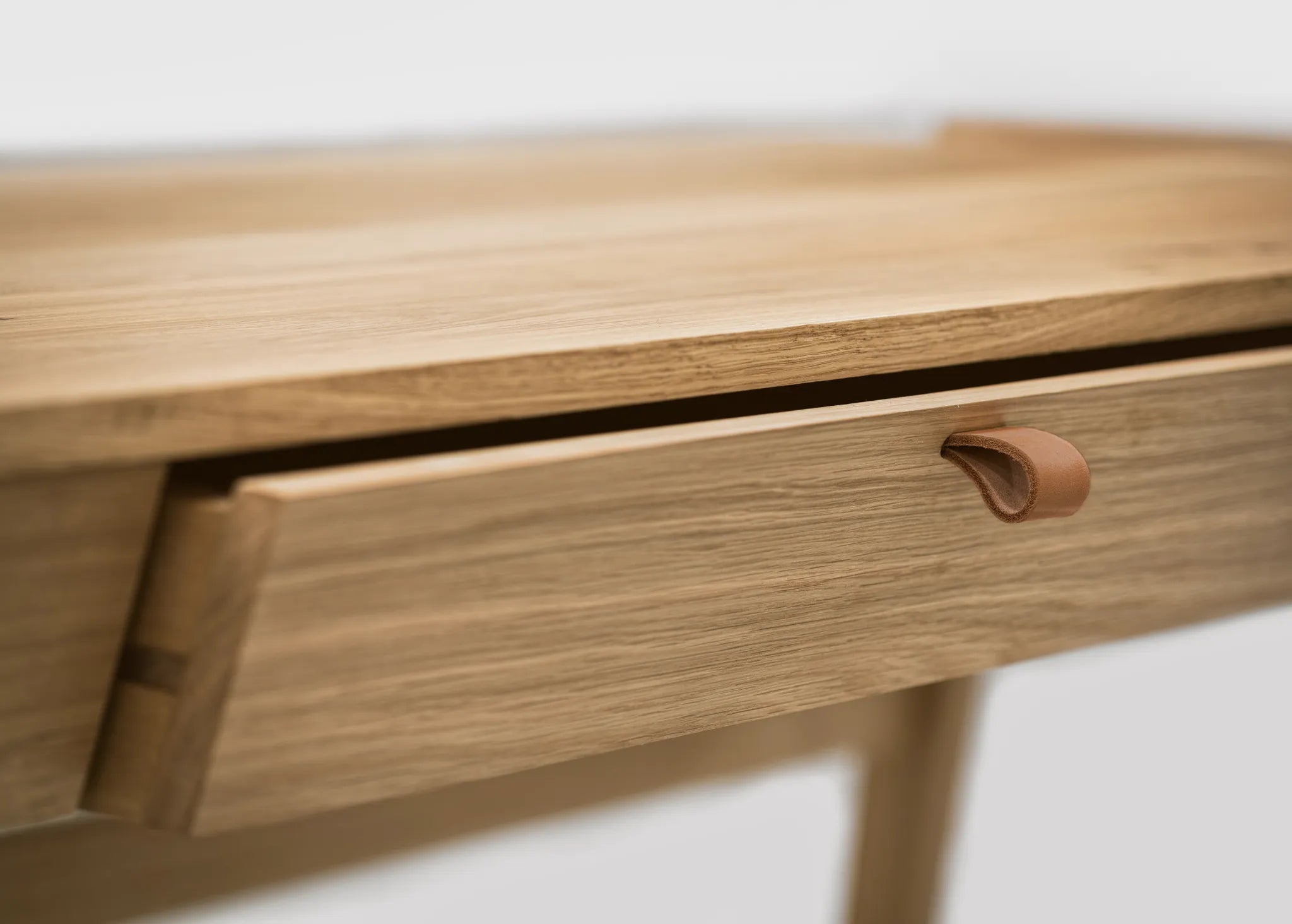 Detail of oak grain on wood desk with drawers and leather handle standing on a white background 