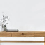Front view of solid wood desk with drawer, crafted from solid oak with a vase and branches a white background
