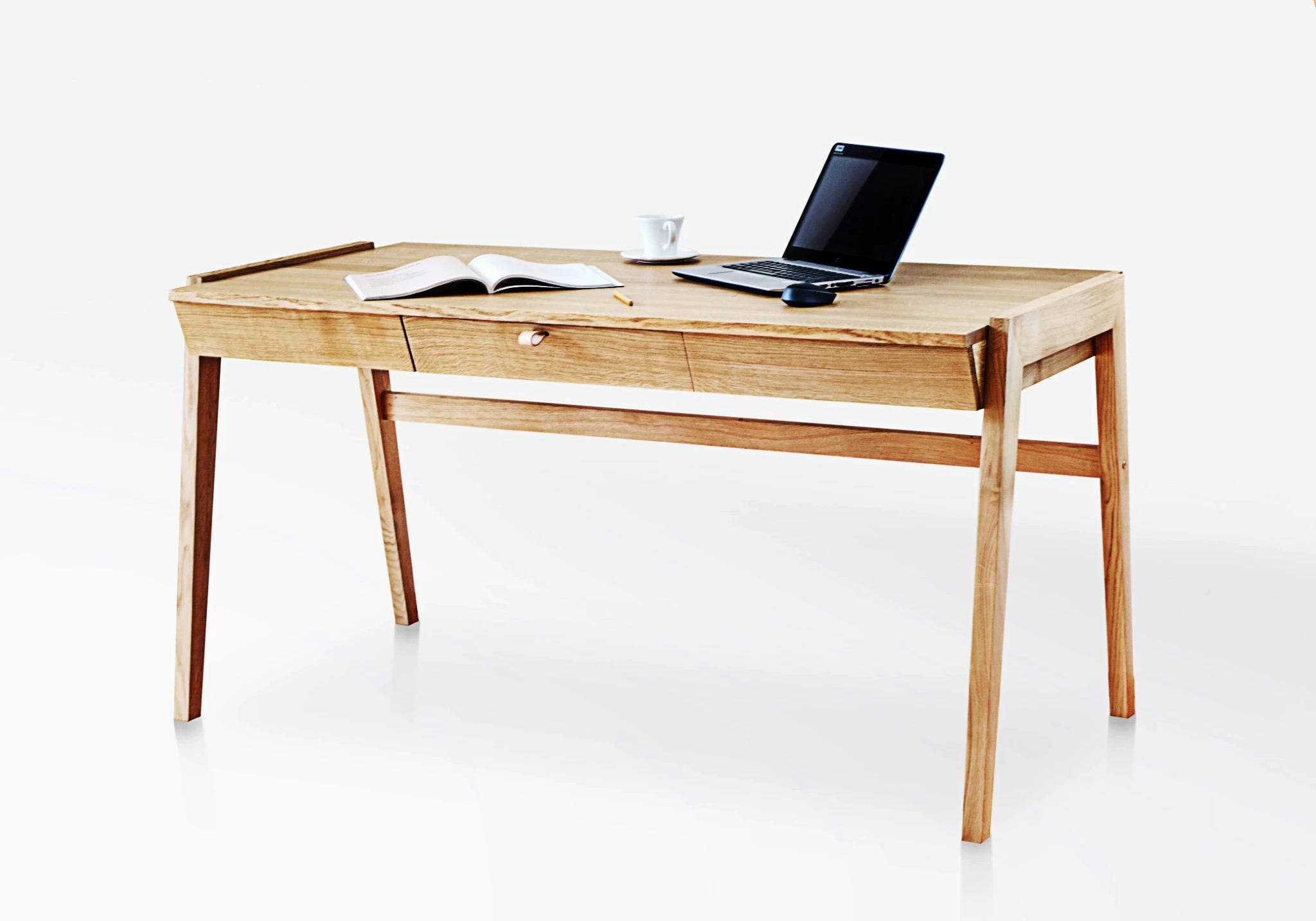Solid wood desk with drawers standing on white background with latop and magazine on oak desktop