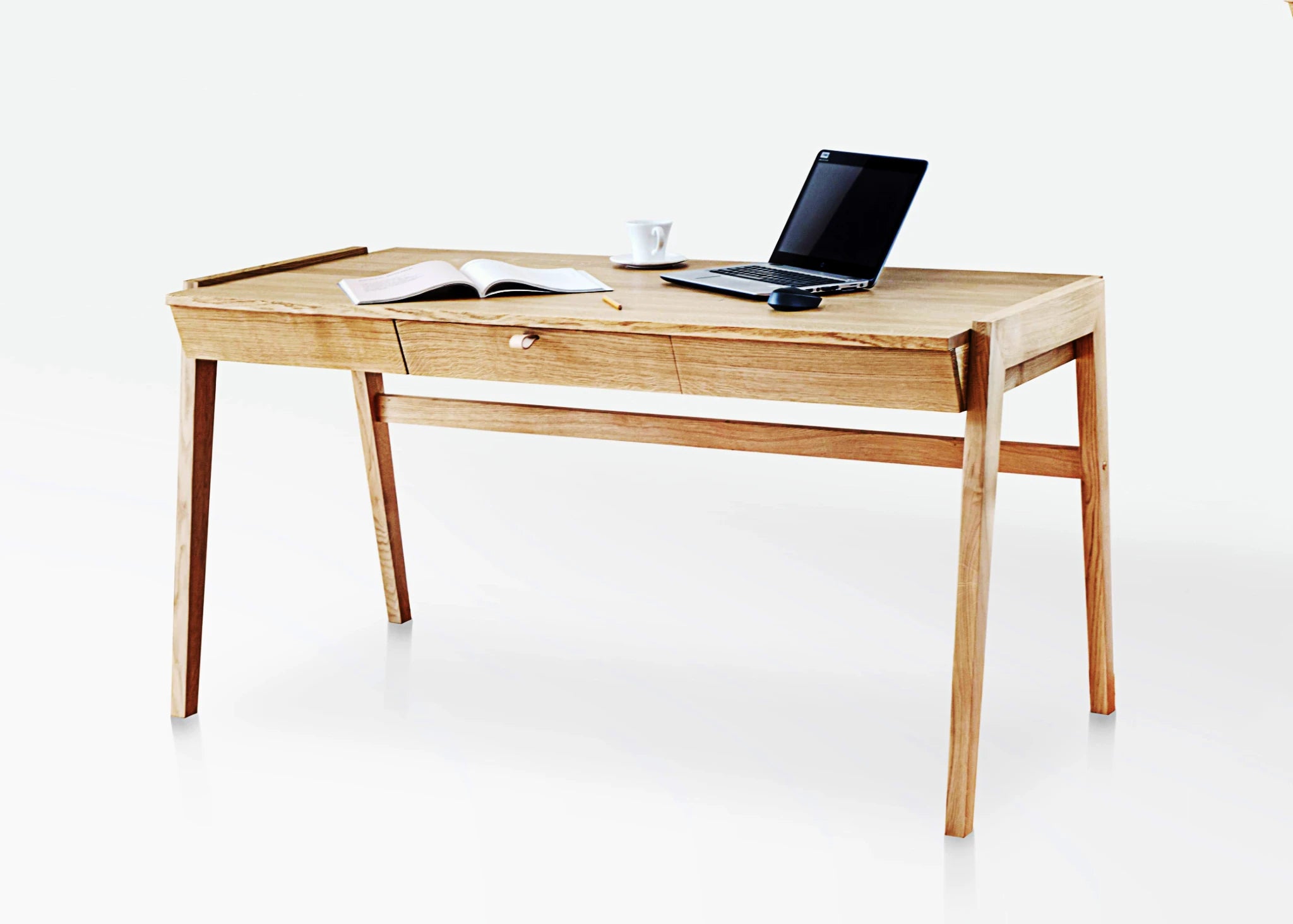 Solid wood desk with drawers standing on white background with latop and magazine on oak desktop