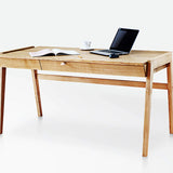 Solid wood desk with drawers standing on white background with latop and magazine on oak desktop