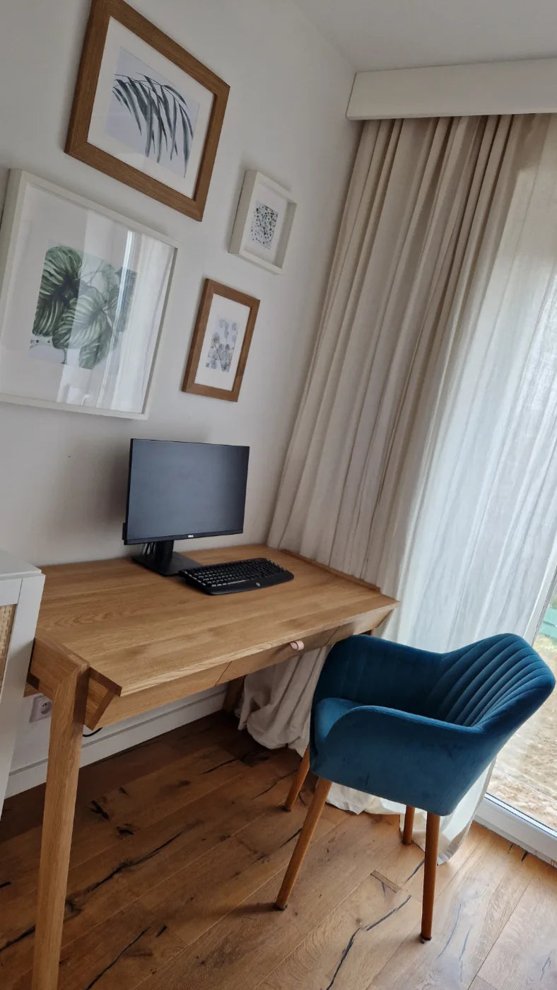 Monitor and keyboard standing on solid oak table top of wooden desk wit drawer in living room