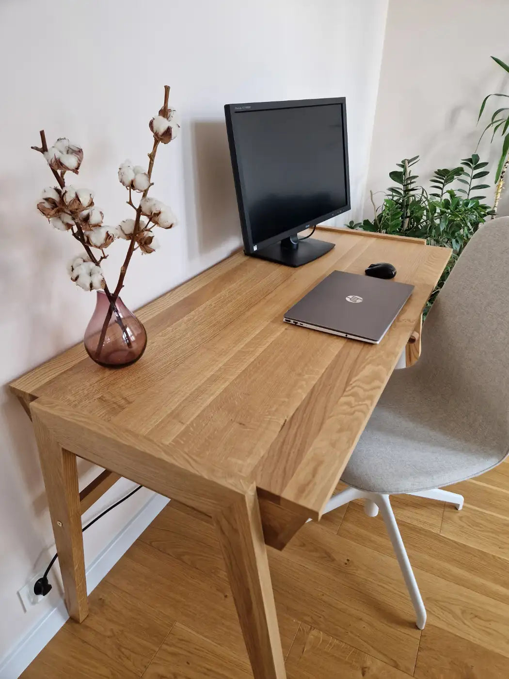 Laptop on table top of solid wooden desk with oak tapered legs standing in modern living room